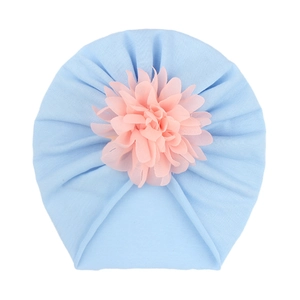Détail du bonnet turban bleu ciel avec décoration de fleur en mousseline rose orangé