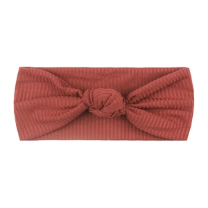 Close-up of ribbed fabric texture on brick red knotted baby headband for infants