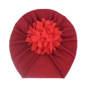 Détail d'un bonnet turban bordeaux pour bébé avec une grande fleur en tissu rouge vif