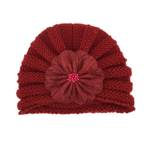 Detail of burgundy knit baby hat featuring a large fabric flower with pink bead center
