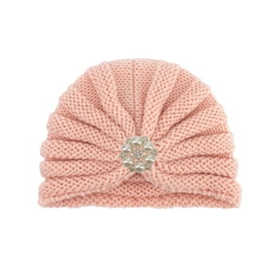 Détail d'un turban en tricot rose pour bébé avec une fleur ornée de perles et strass