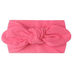 Detail of bright pink nylon baby headband featuring a soft knit fabric bow design