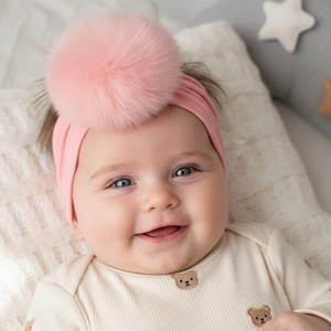 Close-up of soft pink nylon baby headband with a fluffy faux fur pompom detail