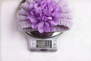 Detailed close-up of a purple knitted headband with a large laser-cut 3D flower decoration