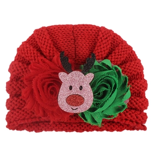 Detail der roten gestrickten Babymütze mit Rentier-Cartoon und Chiffon-Blumen