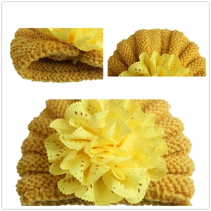 Yellow knit baby hat with handmade lace flower decoration and warm knit texture