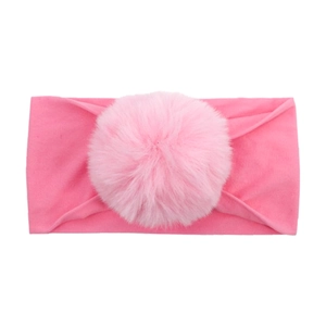 Detail of bright pink elastic baby headband featuring a large fluffy faux fur pompom
