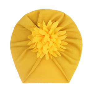 Détail d'un turban pour bébé jaune gingembre avec une grande fleur en tissu 3D multicouche