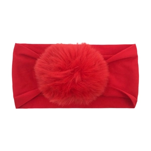 Detail of red elastic nylon baby headband with a soft oversized matching pom-pom ball decoration