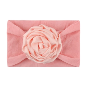 Detailed view of pink nylon baby headband featuring a satin ribbon rose flower decoration