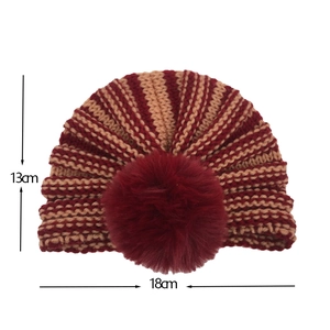 Vista dettagliata del berretto in maglia a righe per neonati con pompon bordeaux