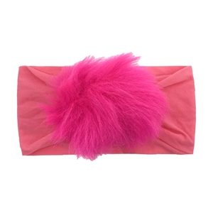 Detailed close-up of a pink elastic nylon headband with a large fluffy faux fur pom-pom ball