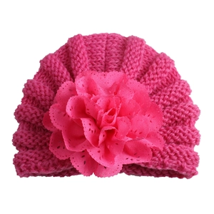 Close-up of rose pink baby knit hat featuring a large layered lace flower decoration