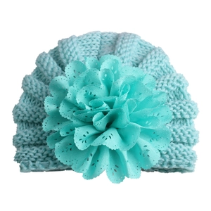 Detail of mint green baby knit hat featuring a large layered lace flower and spiral stitch