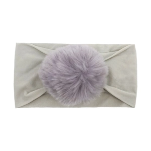 Close-up of soft mint green nylon headband featuring a fluffy purple pom-pom detail