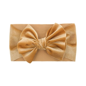 Detailopname van een mosterdgele fluwelen baby hoofdband met een grote handgemaakte strik