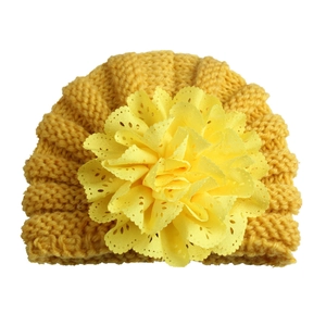 Detailed close-up of bright yellow baby knitted hat with intricate hollowed flower decor