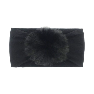 Detail of baby black nylon headband featuring a large soft faux fur pompom decoration