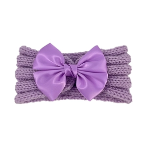Detail of lavender knit baby headband featuring a matching satin ribbon bow on white background