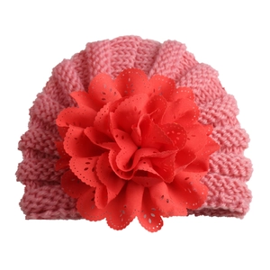 Close-up of pink knit baby turban hat with a large red fabric flower detail