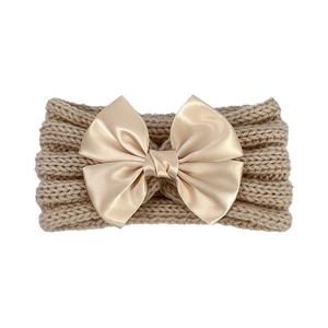 Detail of baby knitted headband with large champagne satin bow and ribbed texture