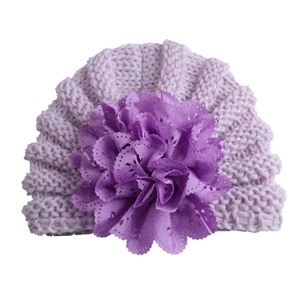 Detailed knit texture of light purple baby hat with a large purple lace flower