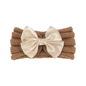Close-up of brown ribbed knit baby headband with a large champagne satin bow detail