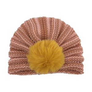 Dettaglio del cappello in maglia rosa a righe per neonati con grande pompon giallo
