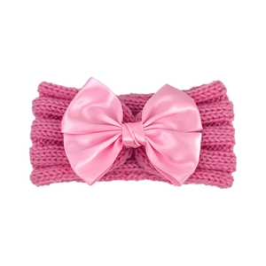 Close-up of pink knitted baby headband featuring a large satin bow with soft texture