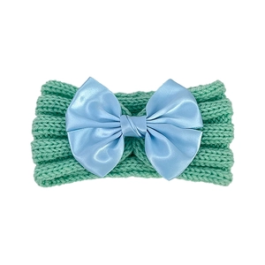 Detail of mint green knitted baby headband with a shiny light blue satin bow
