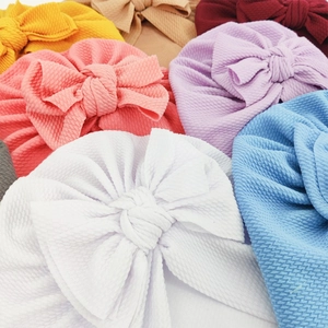 Close-up of soft ribbed knit baby turbans with large bows in various pastel colors
