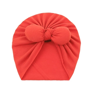 Detail of red baby turban hat with oversized bow made of soft knitted cotton fabric