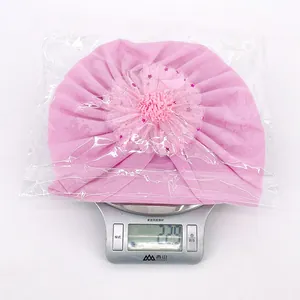 Détail du turban rose pour bébé avec grande fleur en maille placé sur une balance