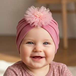 Détail d'un turban bébé avec fleur en tulle multicouche sur maille rose douce