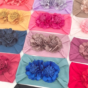 Flat lay of colorful elastic baby headbands with delicate fabric flower decorations