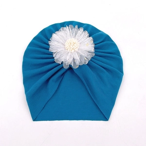 Détail du bonnet turban bébé bleu foncé avec une grande fleur en dentelle blanche