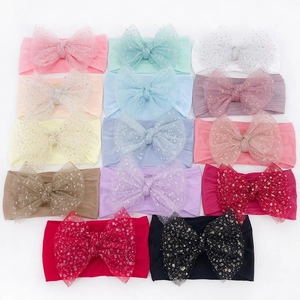 Flat lay of 14 colorful glittery nylon bow headbands for babies on white background