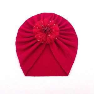 Détail d'un bonnet turban rouge pour bébé avec fleur en tulle et paillettes dorées