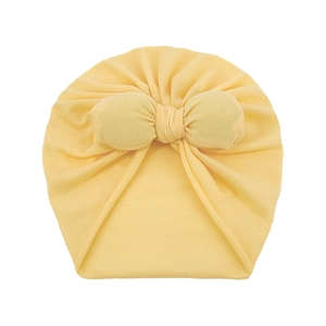 Close-up of light yellow baby turban hat with a large decorative bow and soft knit texture