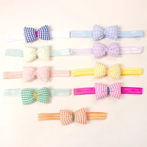 Set of 9 elastic baby headbands with colorful checkered bows on a beige background