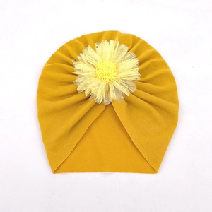 Détail d'un turban pour bébé jaune moutarde avec une grande fleur décorative en tulle