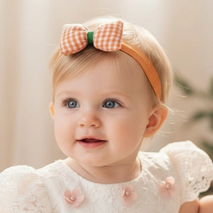 Close-up of cute infant headwrap with orange plaid bow on a soft elastic band