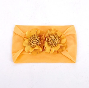 Detailed view of elastic yellow baby headband featuring two layered fabric flower decorations