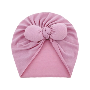 Close-up of pink cotton infant hat featuring a large decorative bow and pleated texture