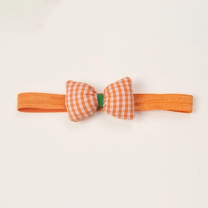 Detail of baby headband with orange gingham bow and green center on soft elastic band
