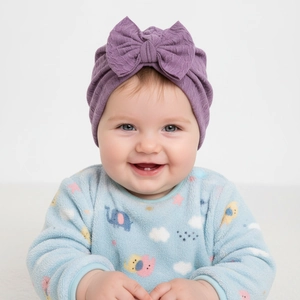 Detail of purple jacquard knit baby turban with large bow on an infant model