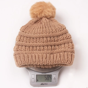 Detailed weight display of a knitted baby beanie with pom-pom on an electronic scale