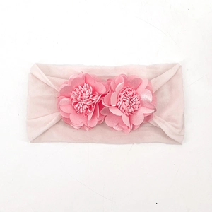 Detail of light pink baby headband featuring two soft fabric flowers with decorative stamens