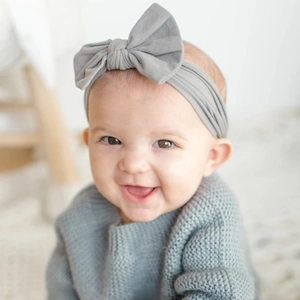 Detailansicht eines weichen grauen Nylon-Babystirnbandes mit großer Schleife am Baby