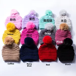 Detail view of 12 multi-colored knitted baby beanies with fluffy faux fur pom poms